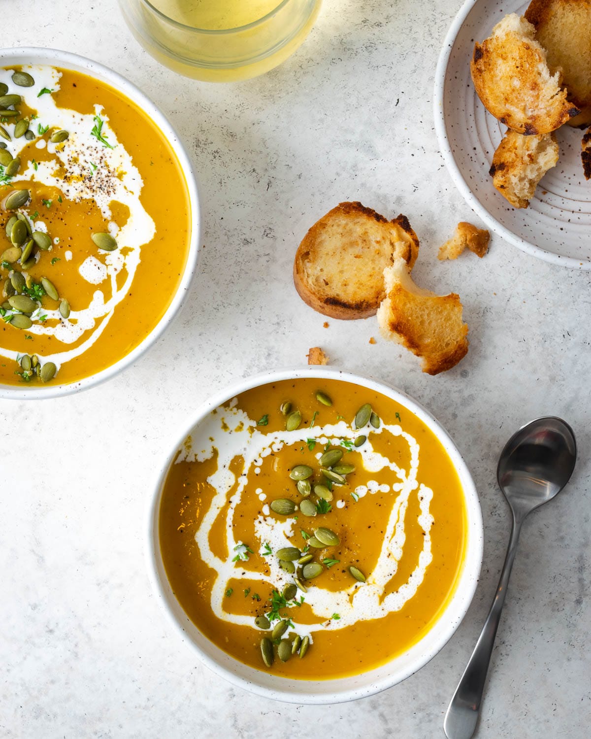soup in a white bowl garnished with cream and pepitas 