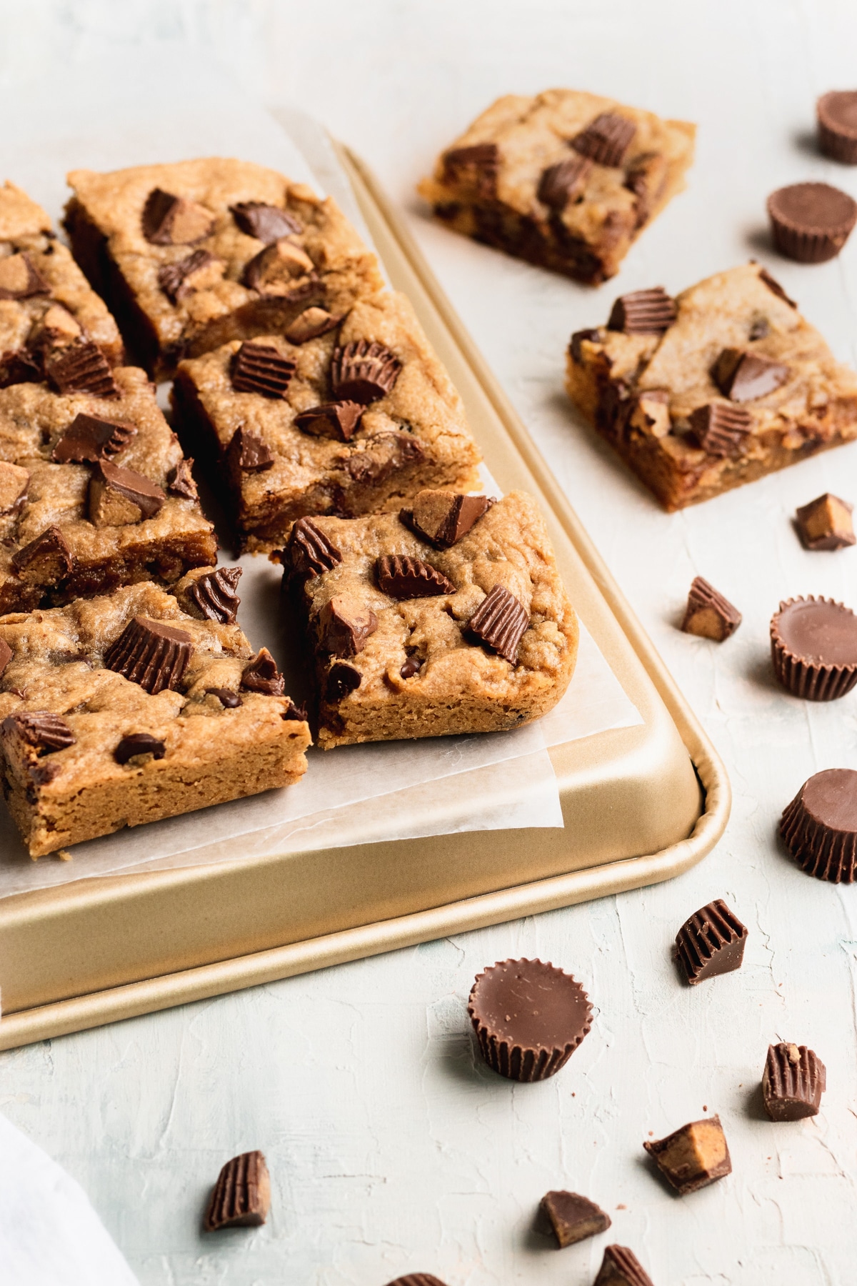 blondies cut into bars on a gold baking sheet lined with parchment paper