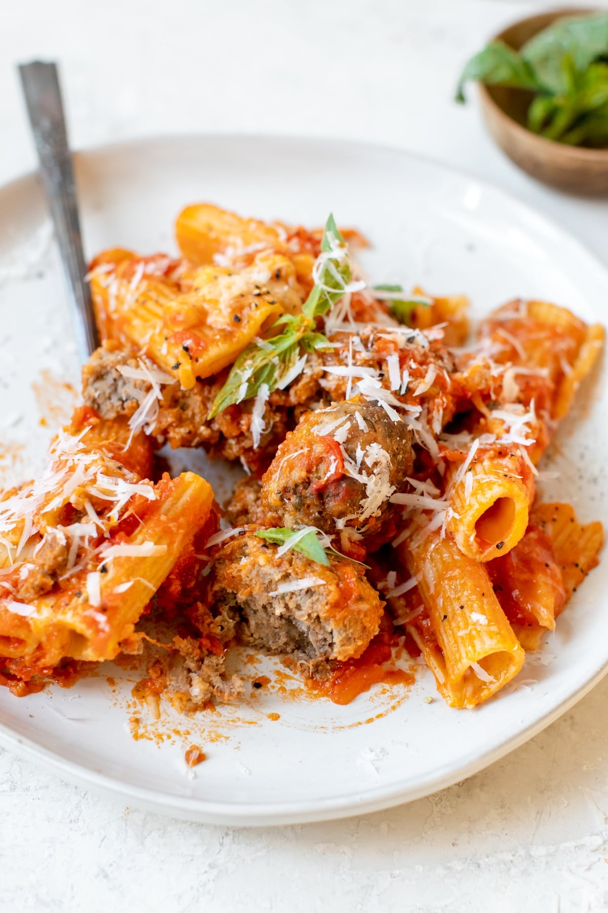 pasta dinner on a white plate garnished with basil and cheese
