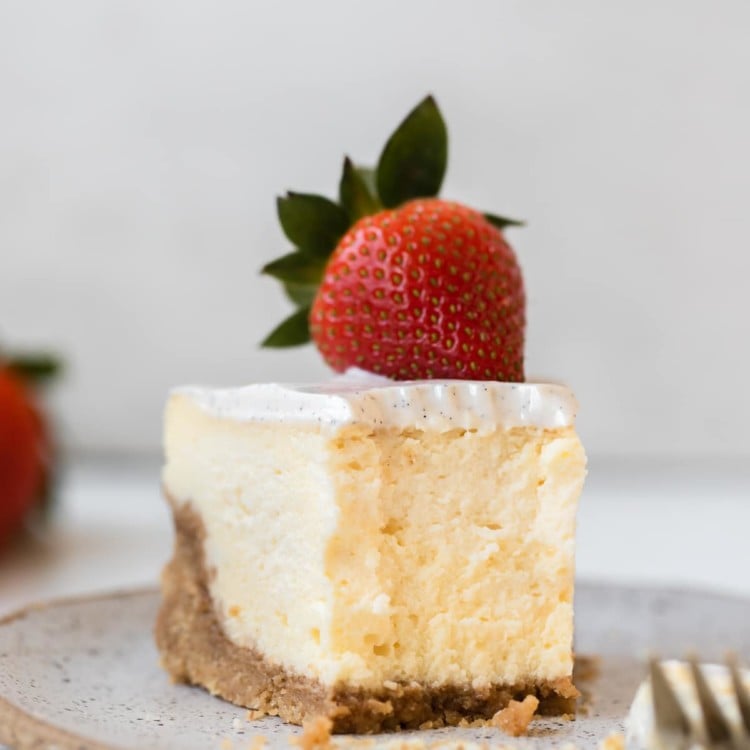a bite taken out of a slice of cheesecake garnished with a strawberry