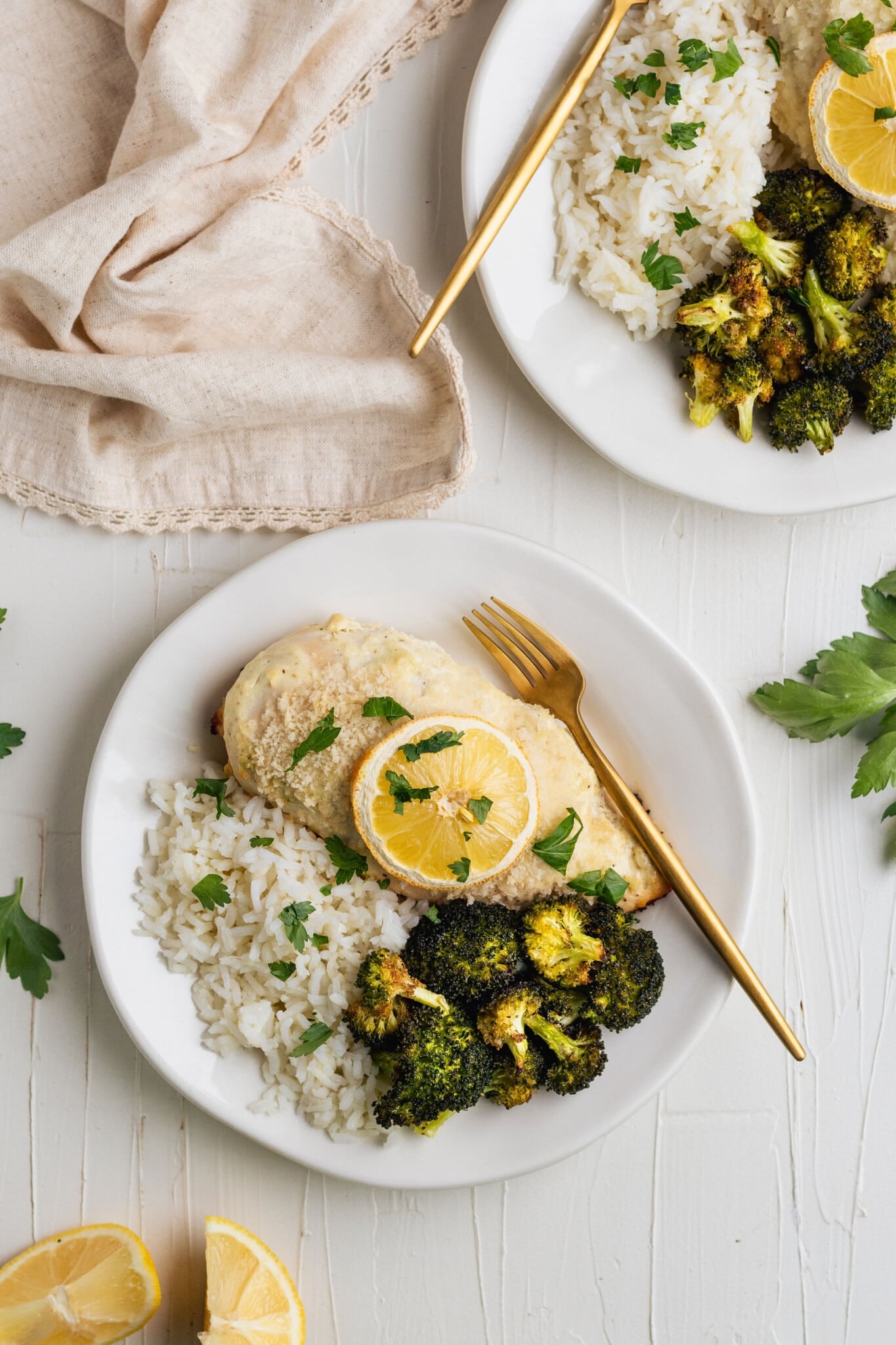 lemon baked chicken on a white plate with roasted broccoli and white rice