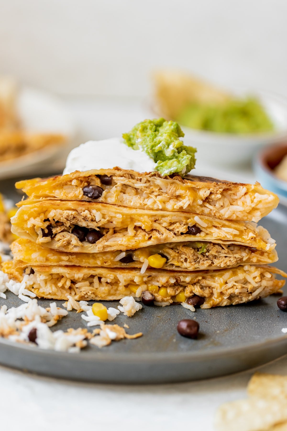 chipotle chicken quesadilla cut in half and stacked on top of each other topped with sour cream and guacamole