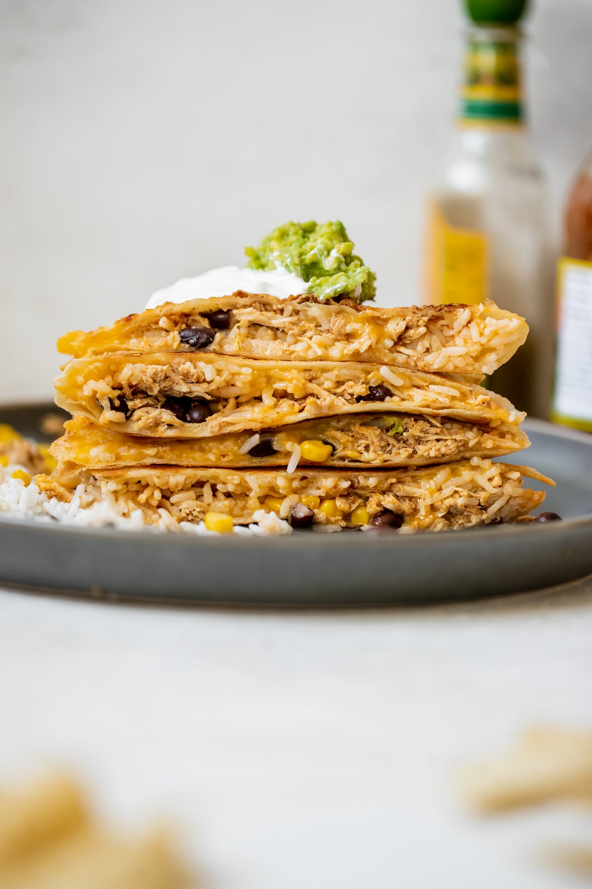 chipotle chicken quesadilla cut in half and stacked on top of each other topped with sour cream and guacamole 