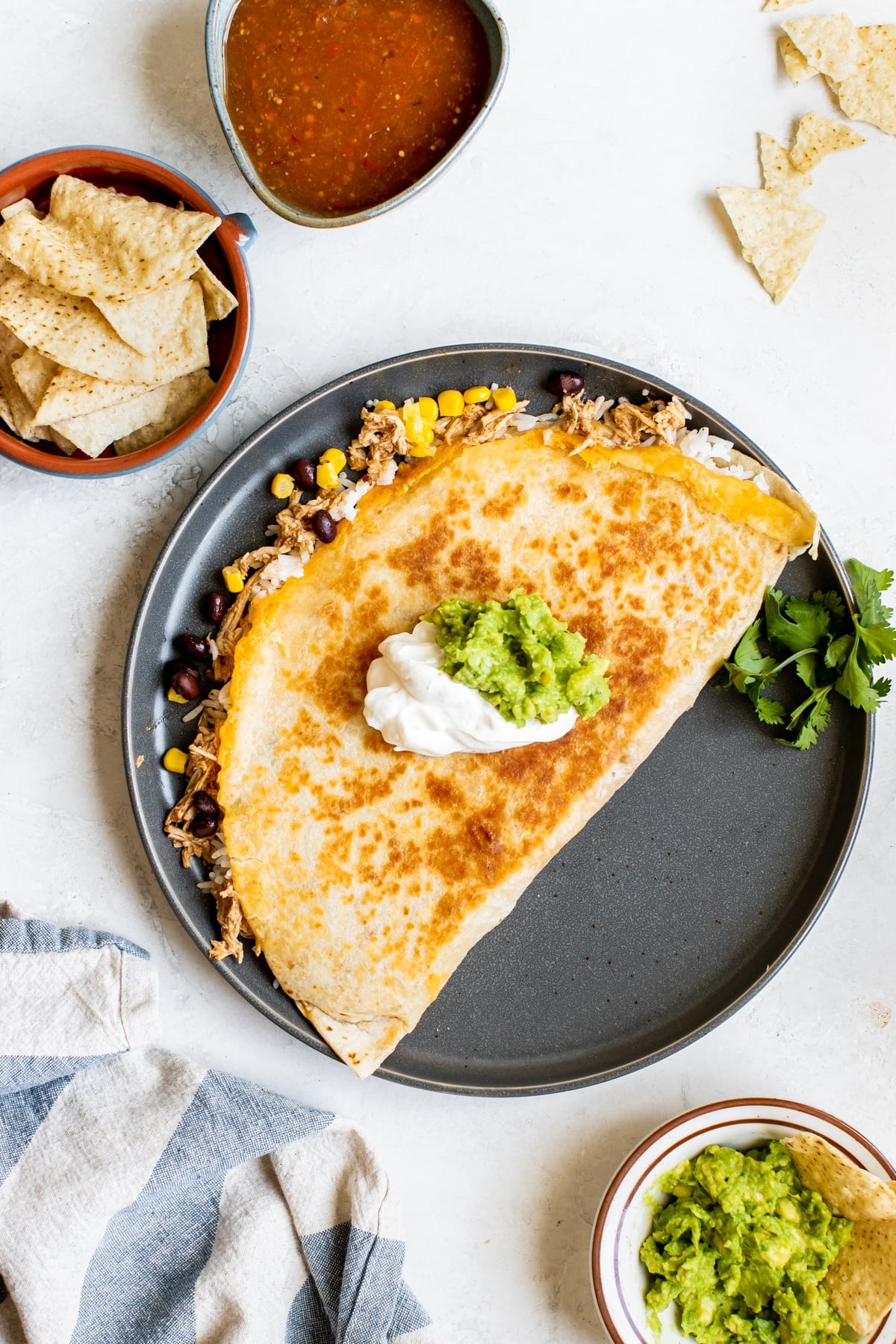 a quesadilla on a blue plate topped with guacamole and sour cream