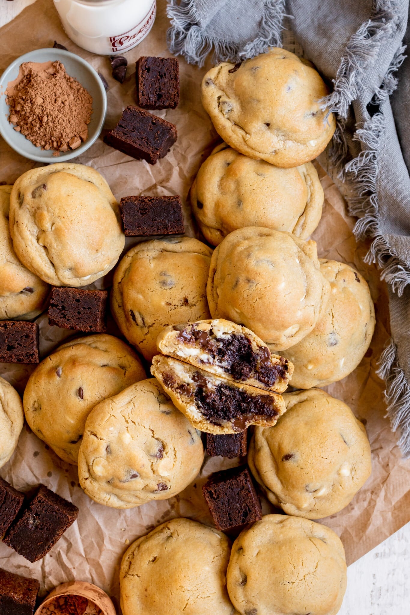 freshly baked cookies on parchment paper with mini brownies and a blue towel.