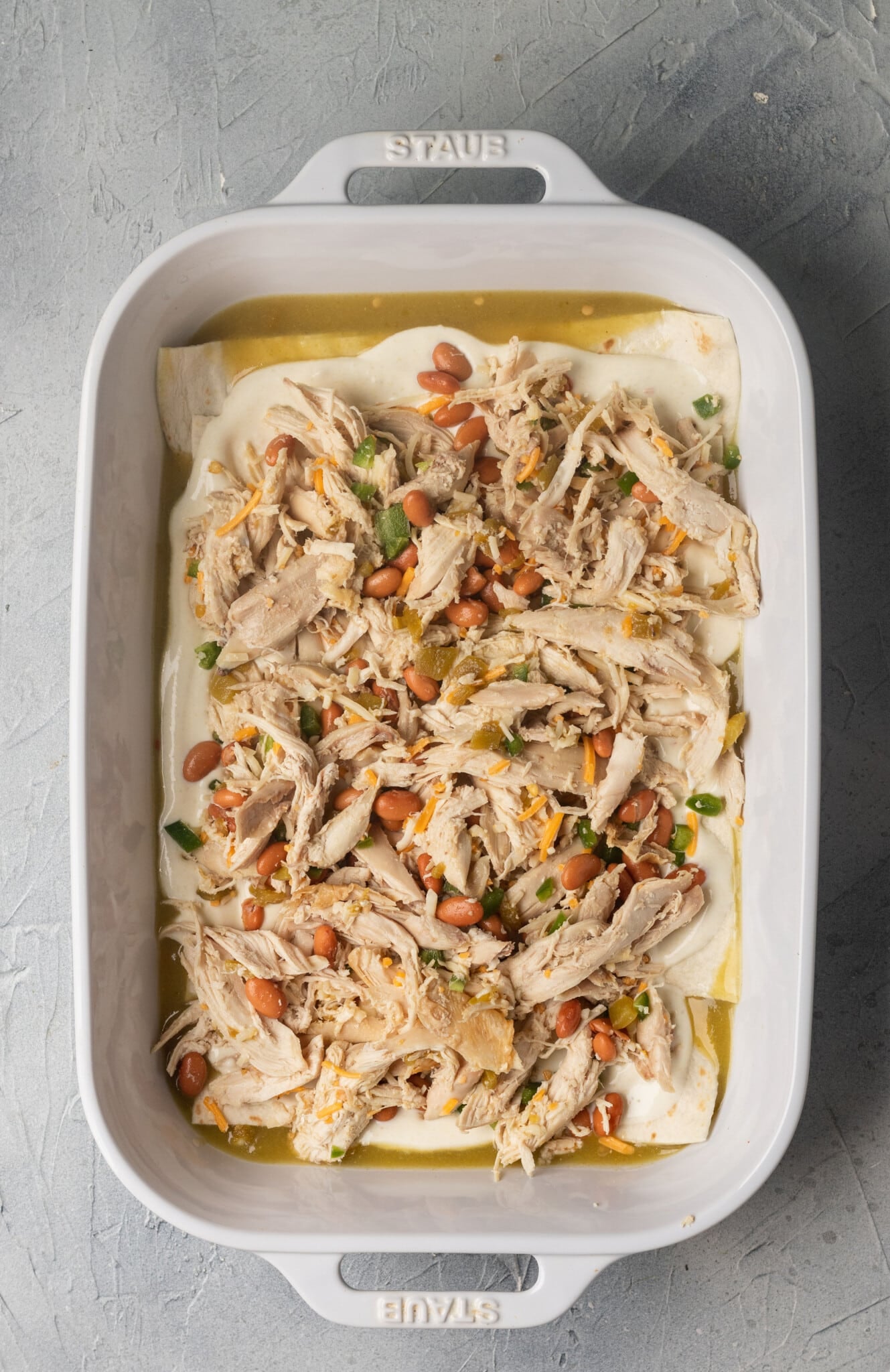 chicken and beans in a white casserole dish.
