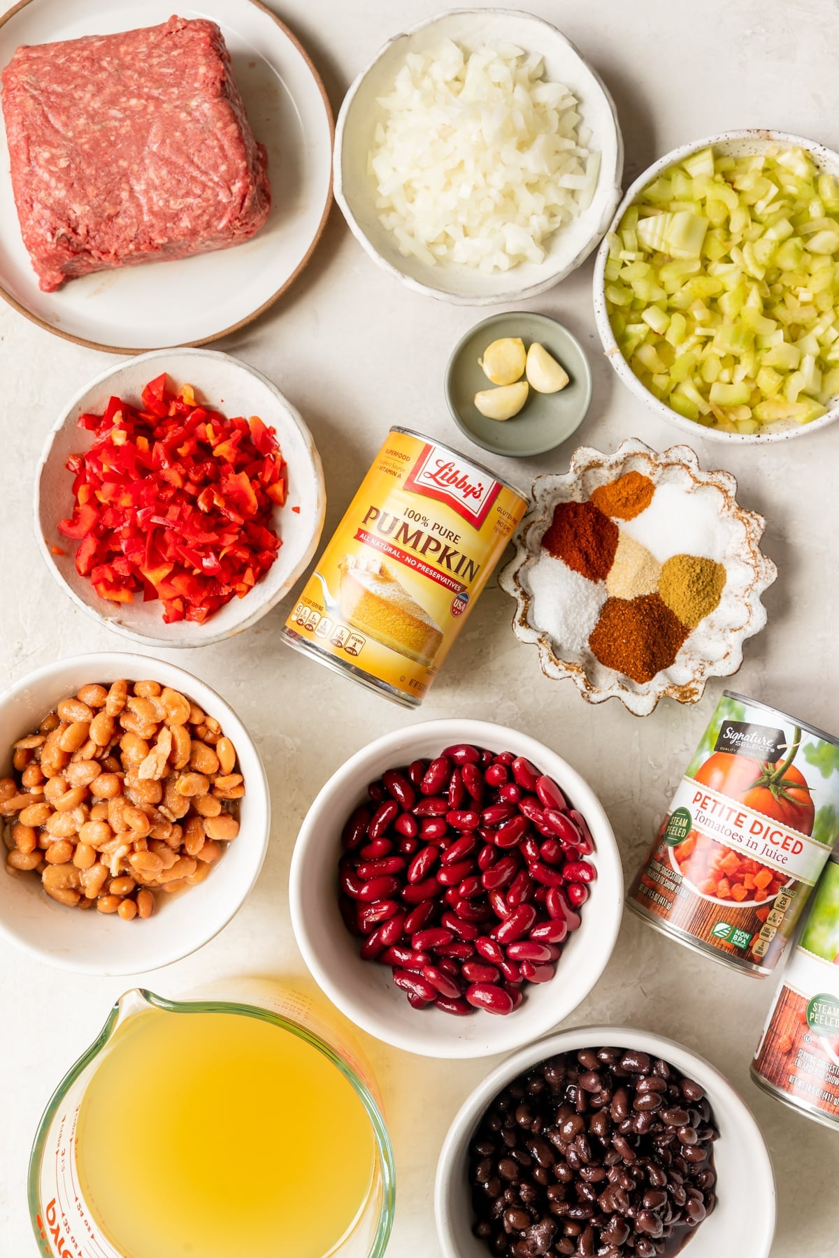 ingredients needed to make chili in small white bowls. 