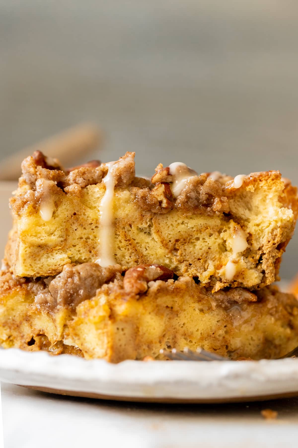 french toast made with pumpkin on a white plate topped with a brown sugar pecan streusel and maple glaze. 