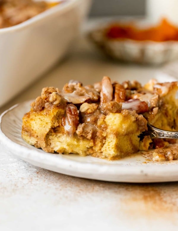 french toast made with pumpkin on a white plate topped with a brown sugar pecan streusel and maple glaze.