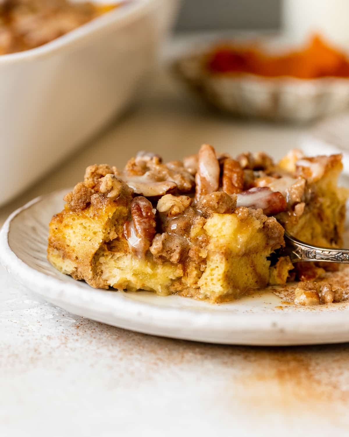 french toast made with pumpkin on a white plate topped with a brown sugar pecan streusel and maple glaze.