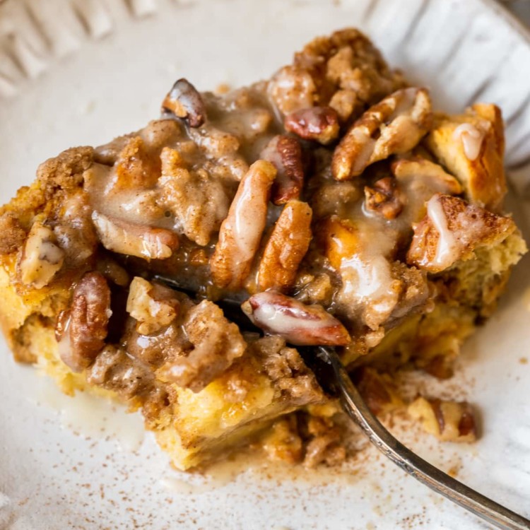 french toast made with pumpkin on a white plate topped with a brown sugar pecan streusel and maple glaze.