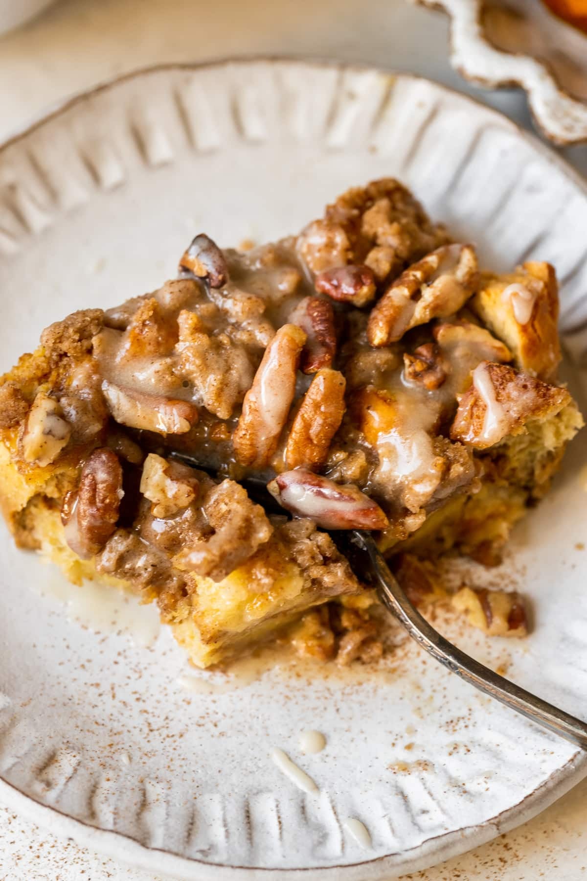 french toast made with pumpkin on a white plate topped with a brown sugar pecan streusel and maple glaze. 