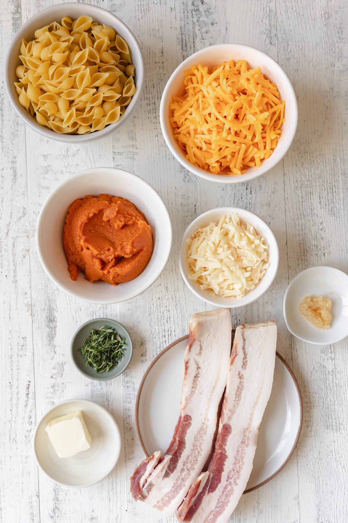 ingredients in small dishes needed to make a macaroni and cheese recipe with bacon and pumpkin. 