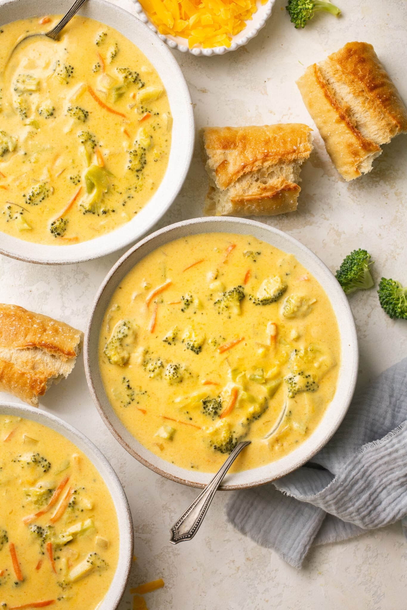 broccoli cheddar soup in a white soup bowl with bread dipping in it. 