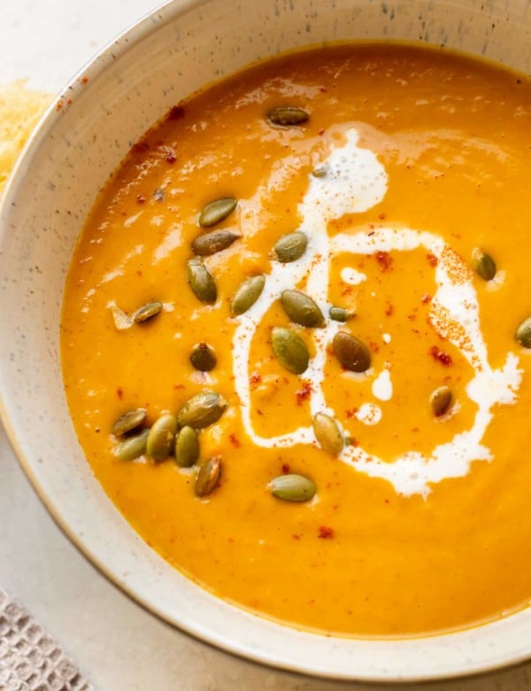 squash soup in a bowl topped with pepitas, cream, and paprika.