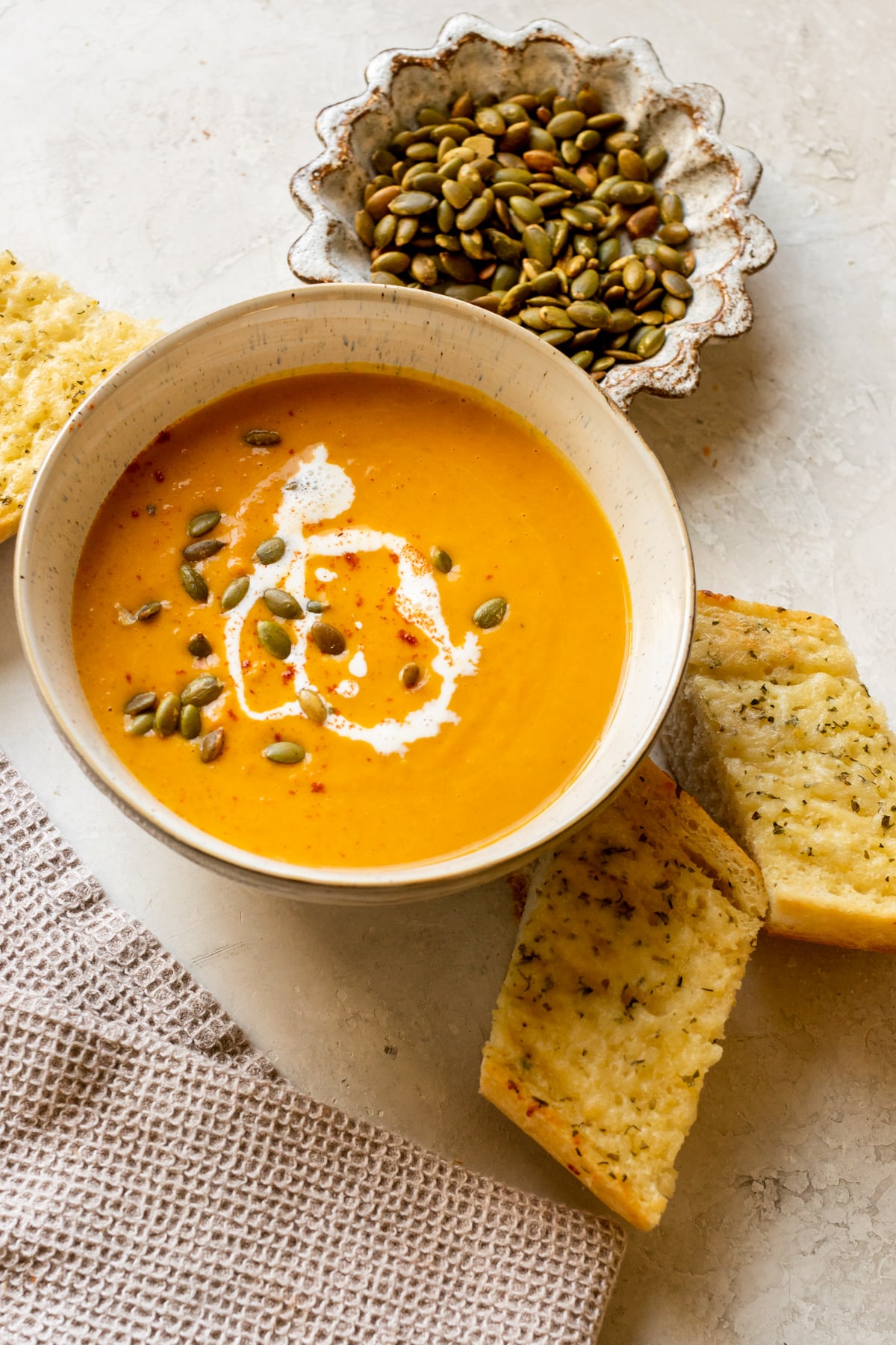 squash soup in a bowl topped with pepitas, cream, and paprika.