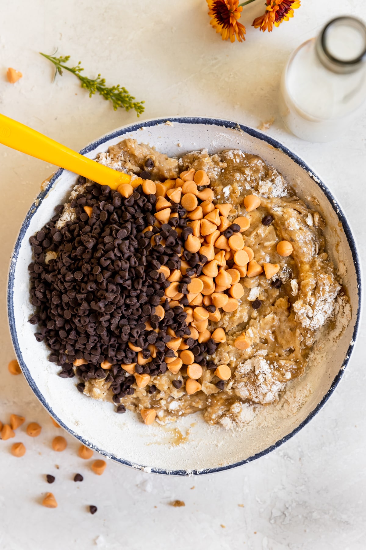 cookie dough in a bowl with chocolate chips and butterscotch chips in it. 