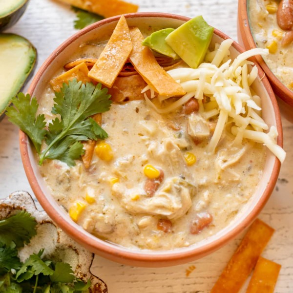 enchilada soup in a bowl garnished with cilantro, tortilla strips, avocado and Monterey Jack cheese.
