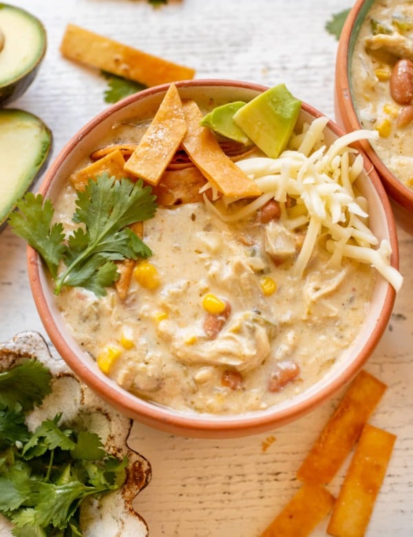 enchilada soup in a bowl garnished with cilantro, tortilla strips, avocado and Monterey Jack cheese.