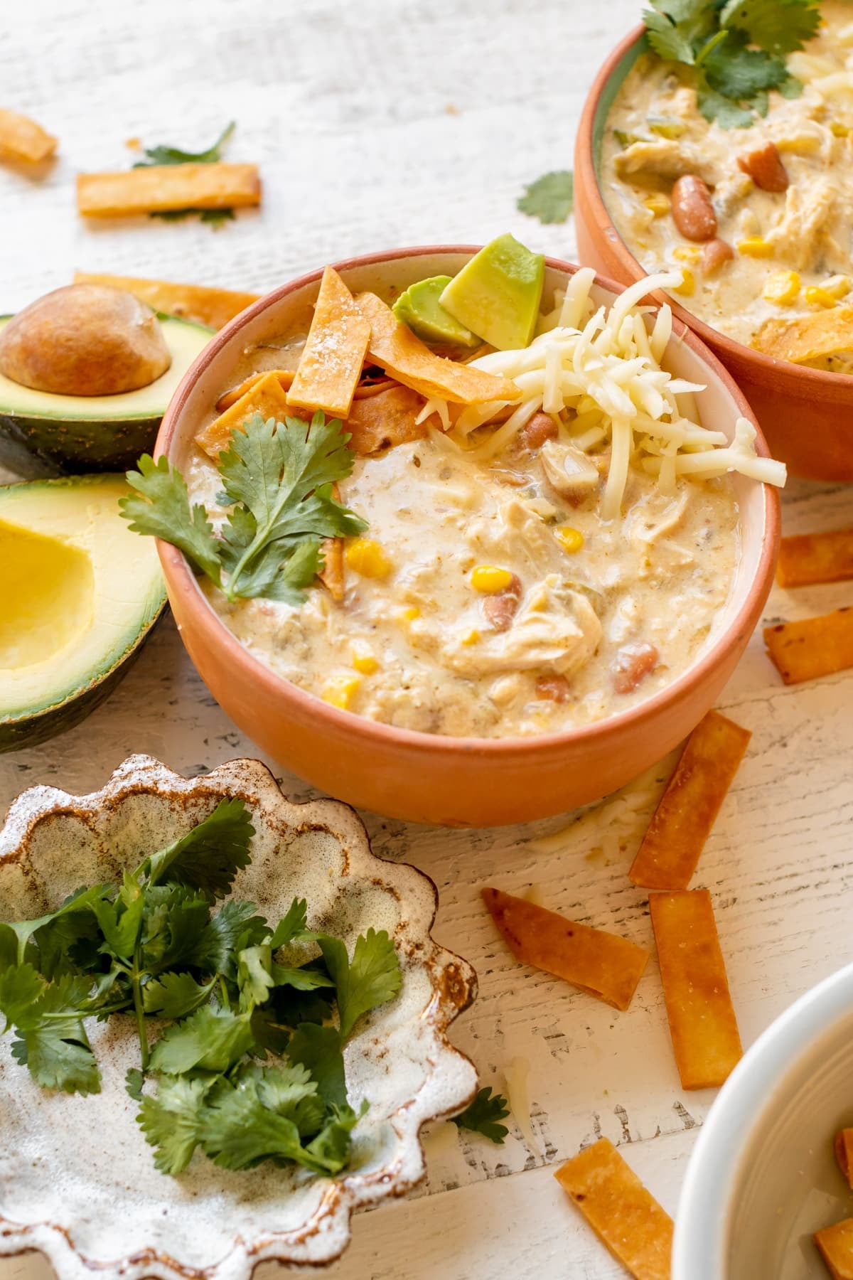 enchilada soup in a bowl garnished with cilantro, tortilla strips, avocado and Monterey Jack cheese. 