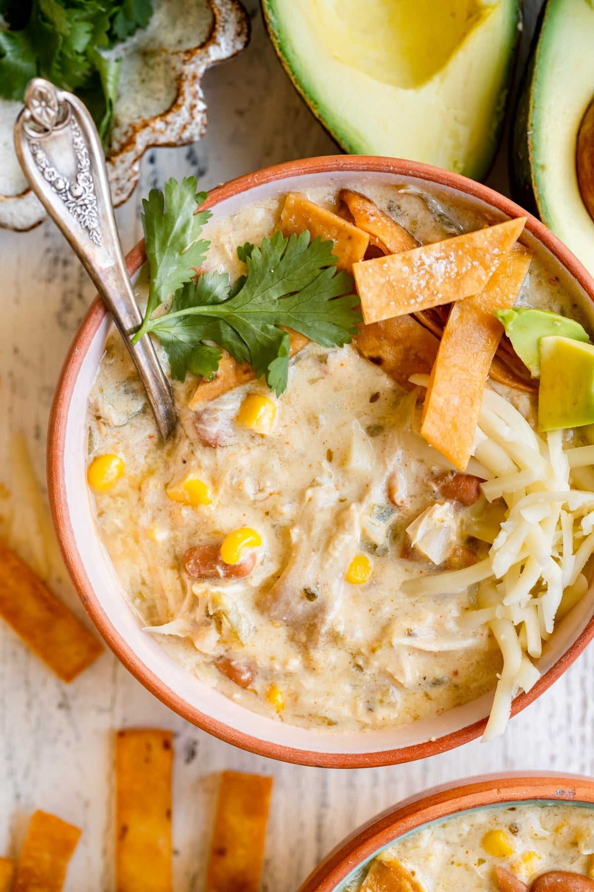 enchilada soup in a bowl garnished with cilantro, tortilla strips, avocado and Monterey Jack cheese. 