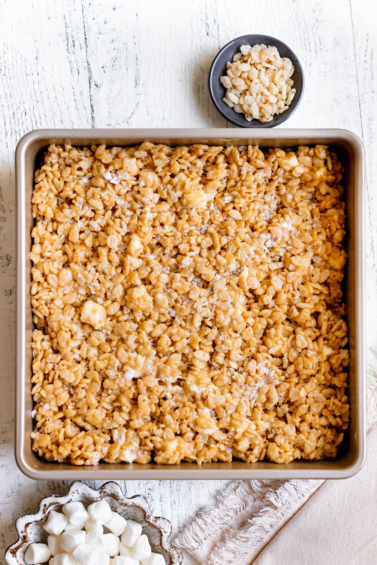 rice krispies pressed in a gold 9x9 pan and garnished with flaky sea salt.