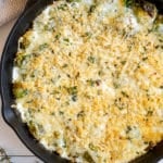 cast iron skilled with creamy brussels sprouts topped with toasted cheese