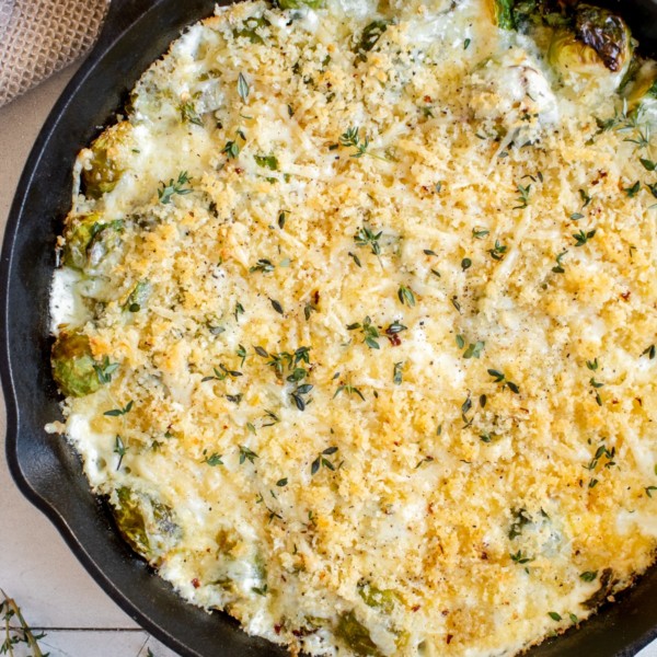 cast iron skilled with creamy brussels sprouts topped with toasted cheese