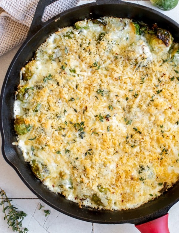 cast iron skilled with creamy brussels sprouts topped with toasted cheese
