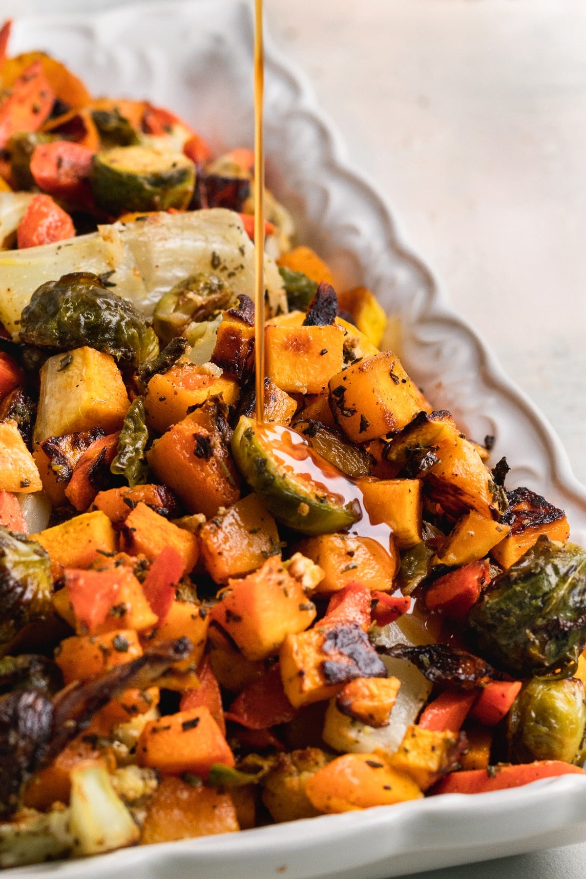cider glaze being poured on roasted veggies. 