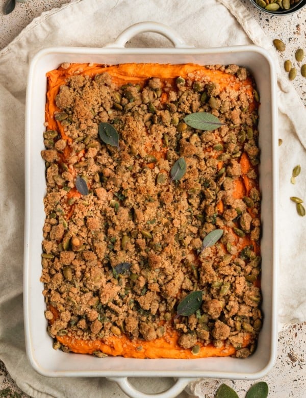 white casserole dish with mashed sweet potatoes & a crumbly topping