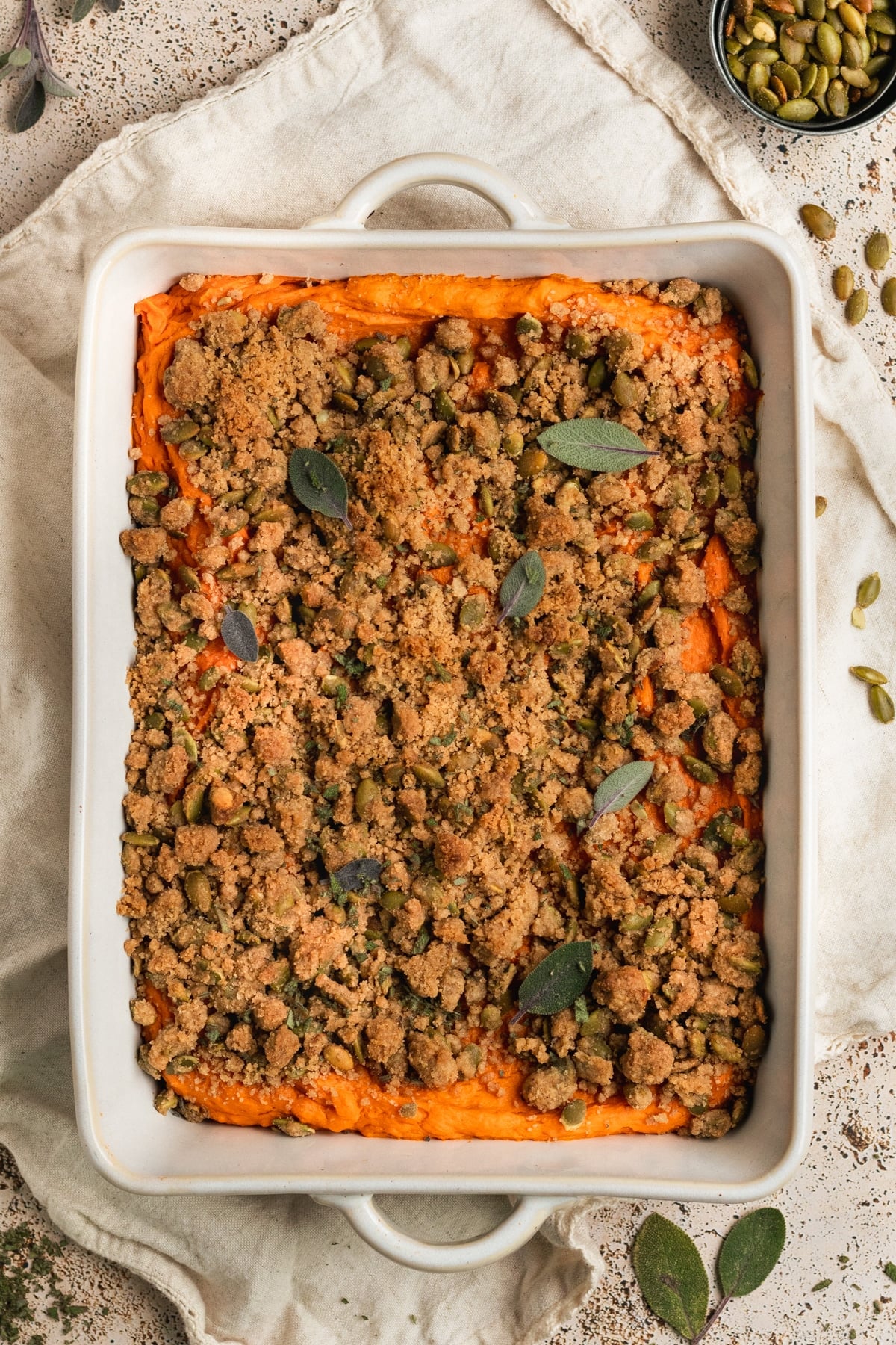 white casserole dish with mashed sweet potatoes & a crumbly topping