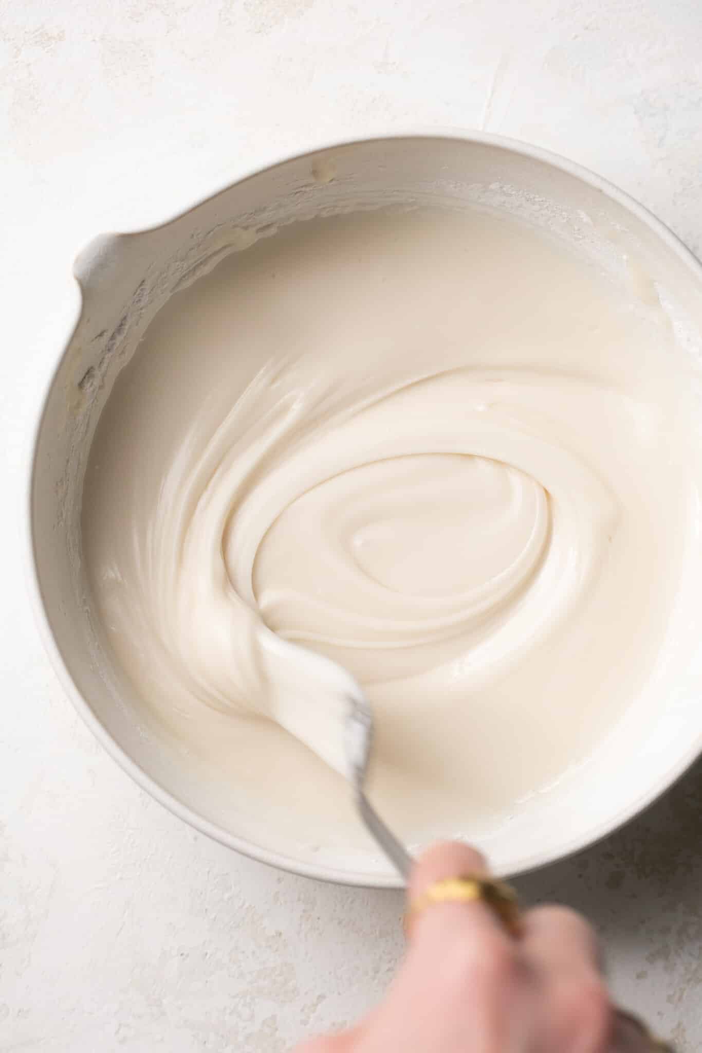 a bowl with frosting inside and a spoon stirring it.