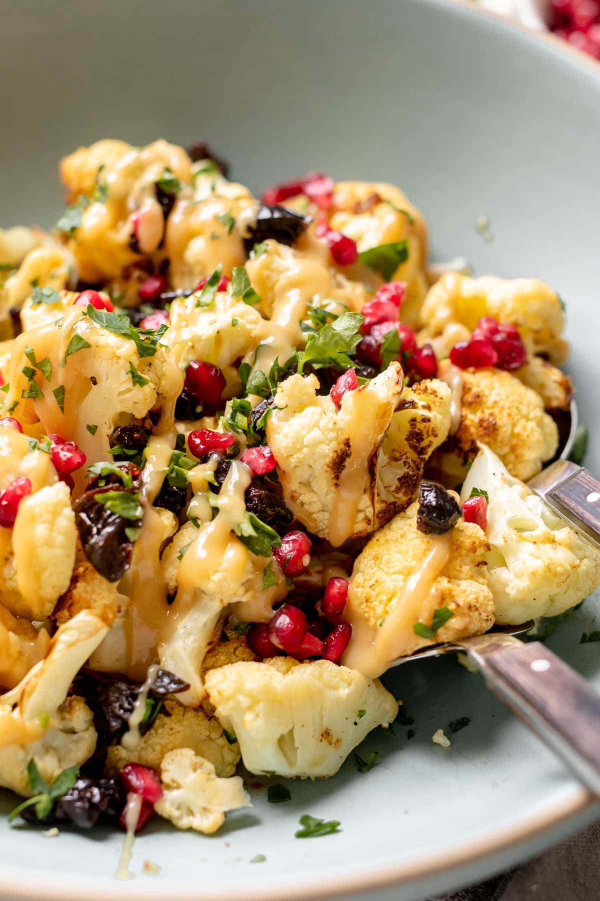 cauliflower in a bowl with tahini honey mustard drizzled on top. 