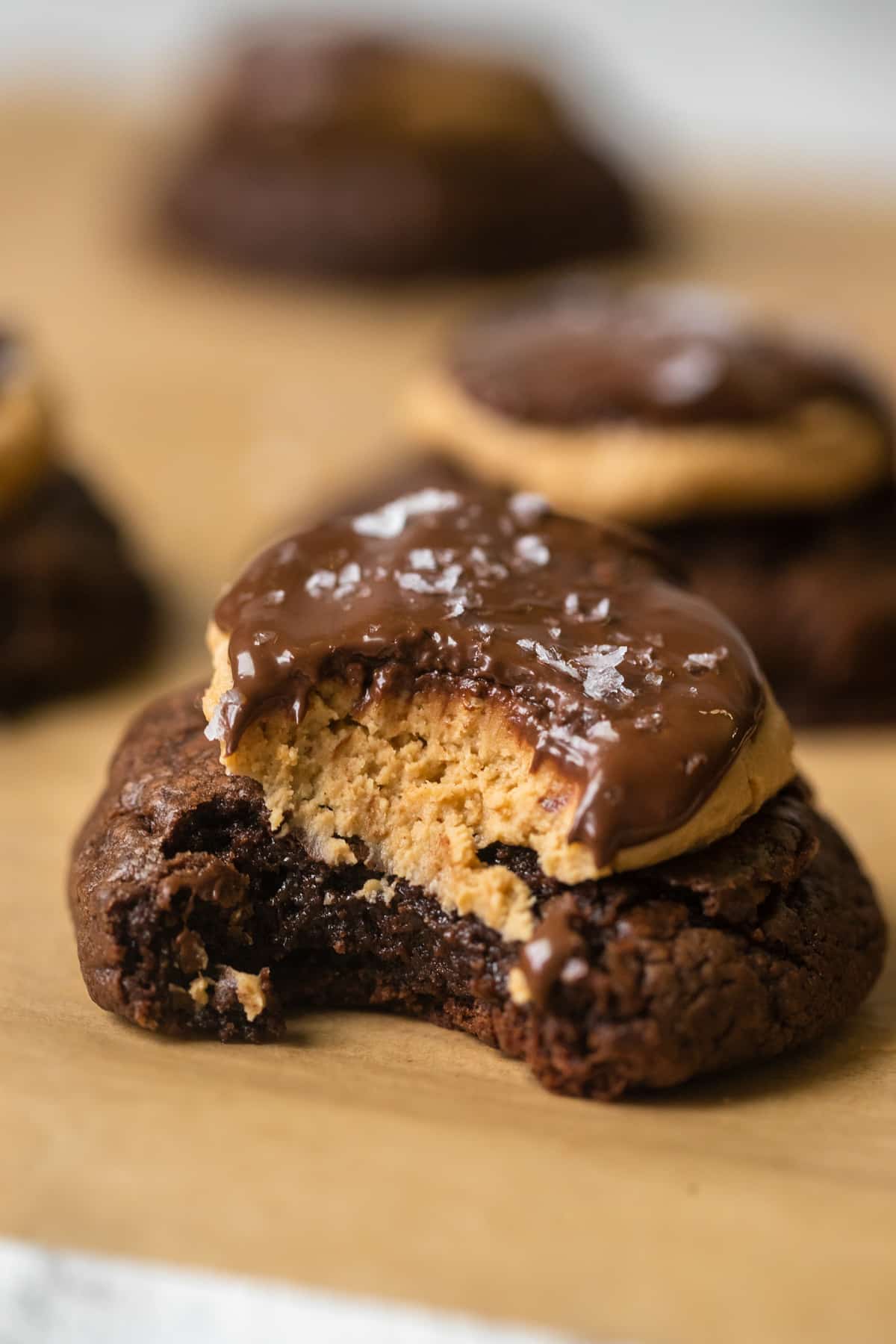 cookies on a baking sheet topped with peanut butter and chocolate with a bite take out of the cookie.