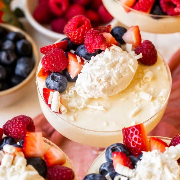 vintage martini glass full of white chocolate mousse topped with berries and white chocoalte shavings.