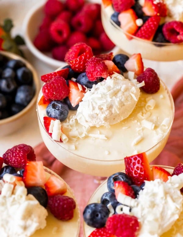 vintage martini glass full of white chocolate mousse topped with berries and white chocoalte shavings.