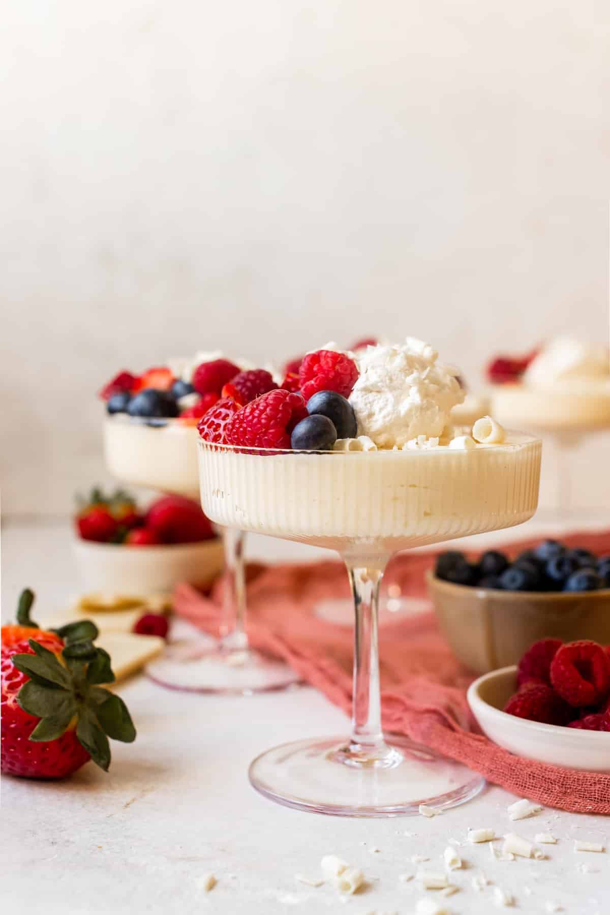 mousse in martini glasses topped with whipped cream and fresh berries.