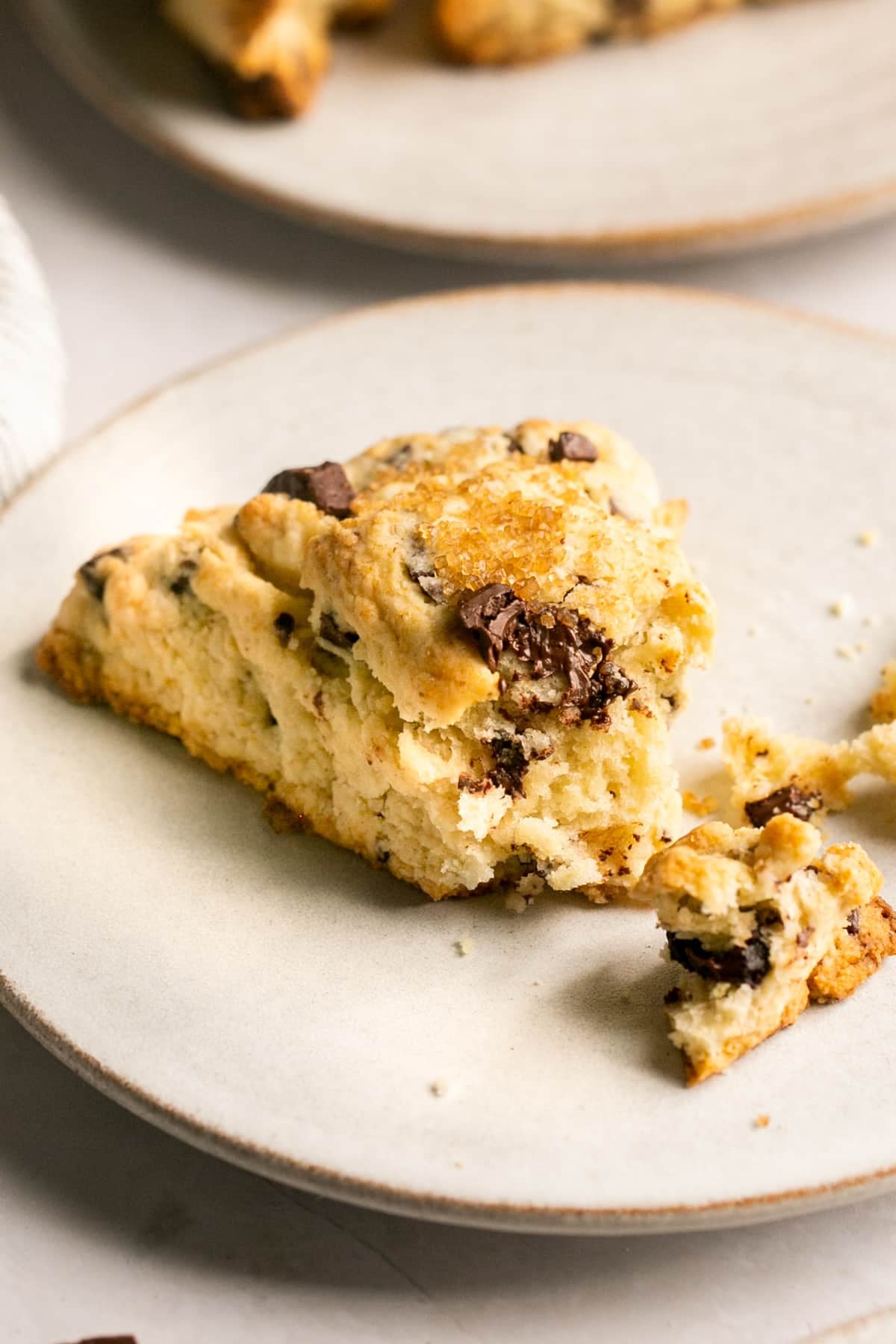 scone on a white plate with a bite taken out of it.