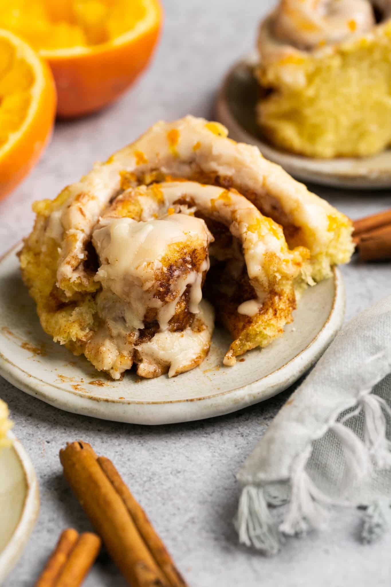 cinnamon roll on a plate with glaze on top and a bite taken from it.