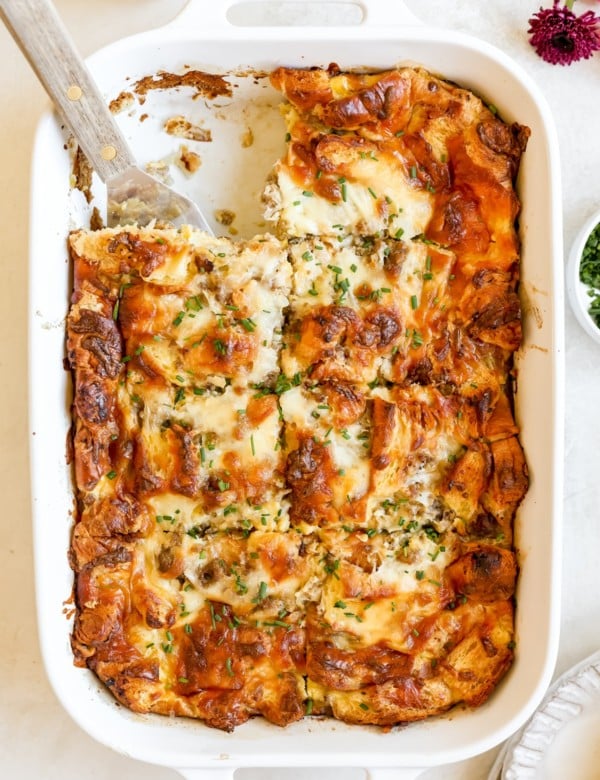 white casserole dish filled with cooked egg and sausage casserole topped with chopped chives