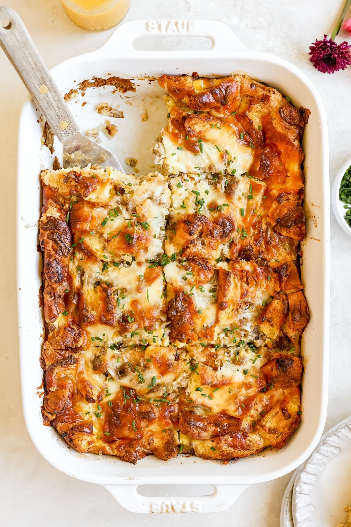 white casserole dish filled with cooked egg and sausage casserole topped with chopped chives