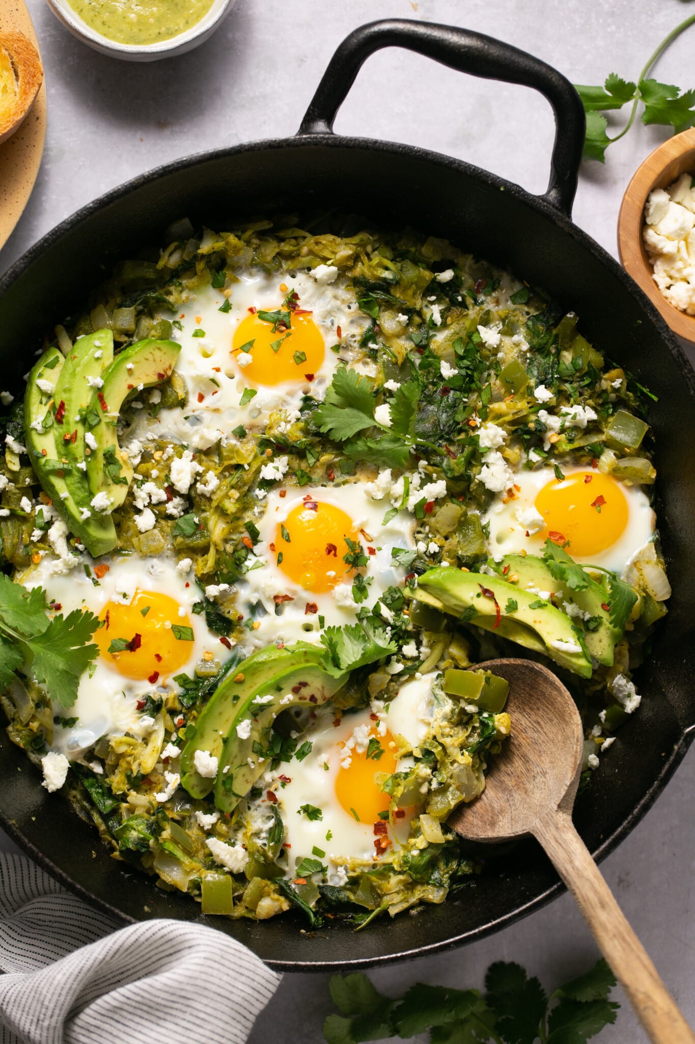 eggs in a skillet with veggies and avocado.