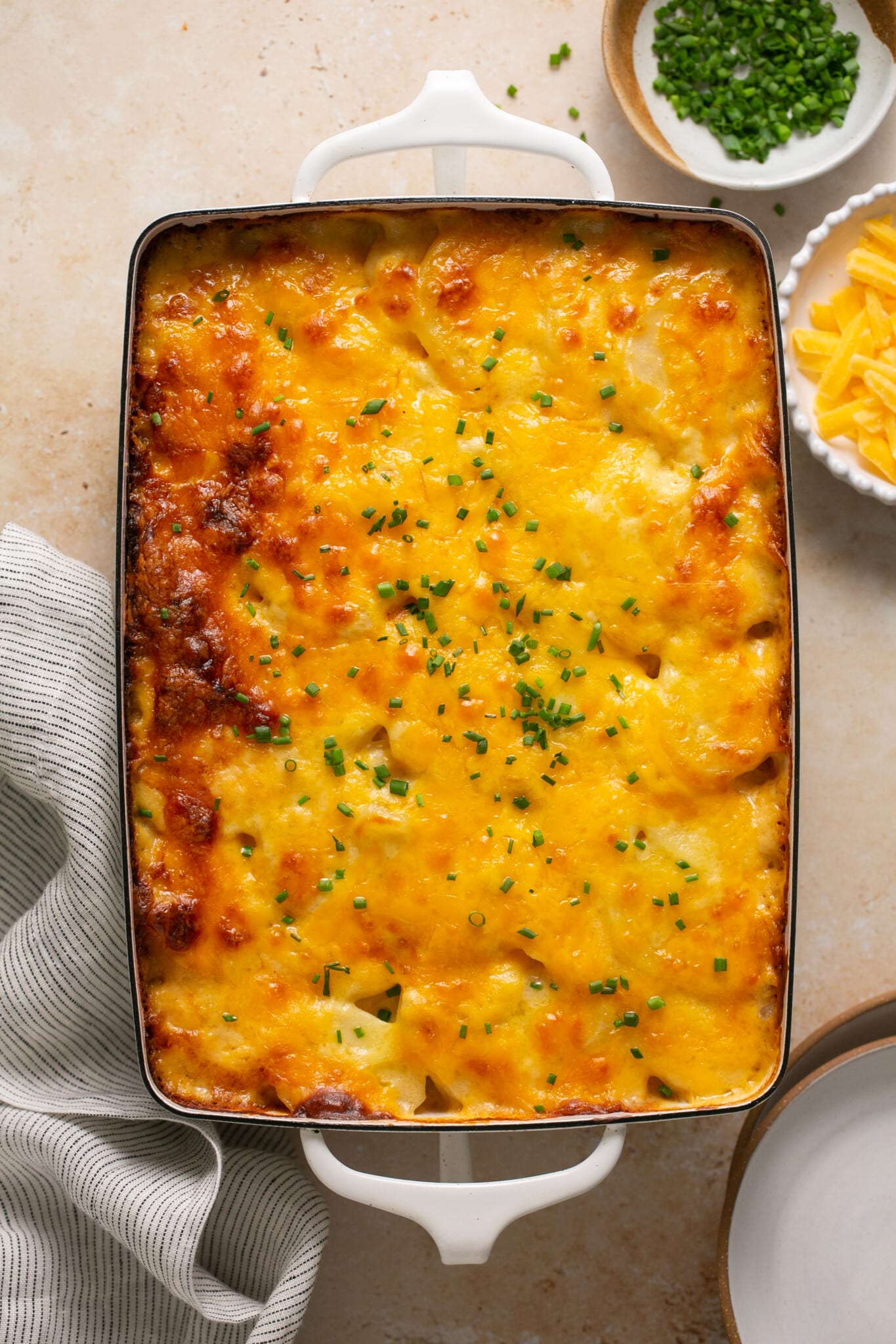 scalloped potatoes with cheddar cheese on top garnished wish chives. 