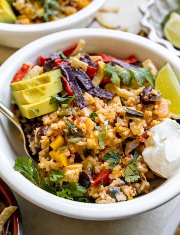 white bowl with rice mixture, avocado, sour cream, and tortilla strips