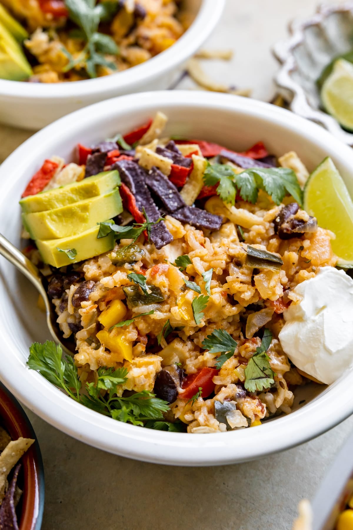 white bowl with rice mixture, avocado, sour cream, and tortilla strips