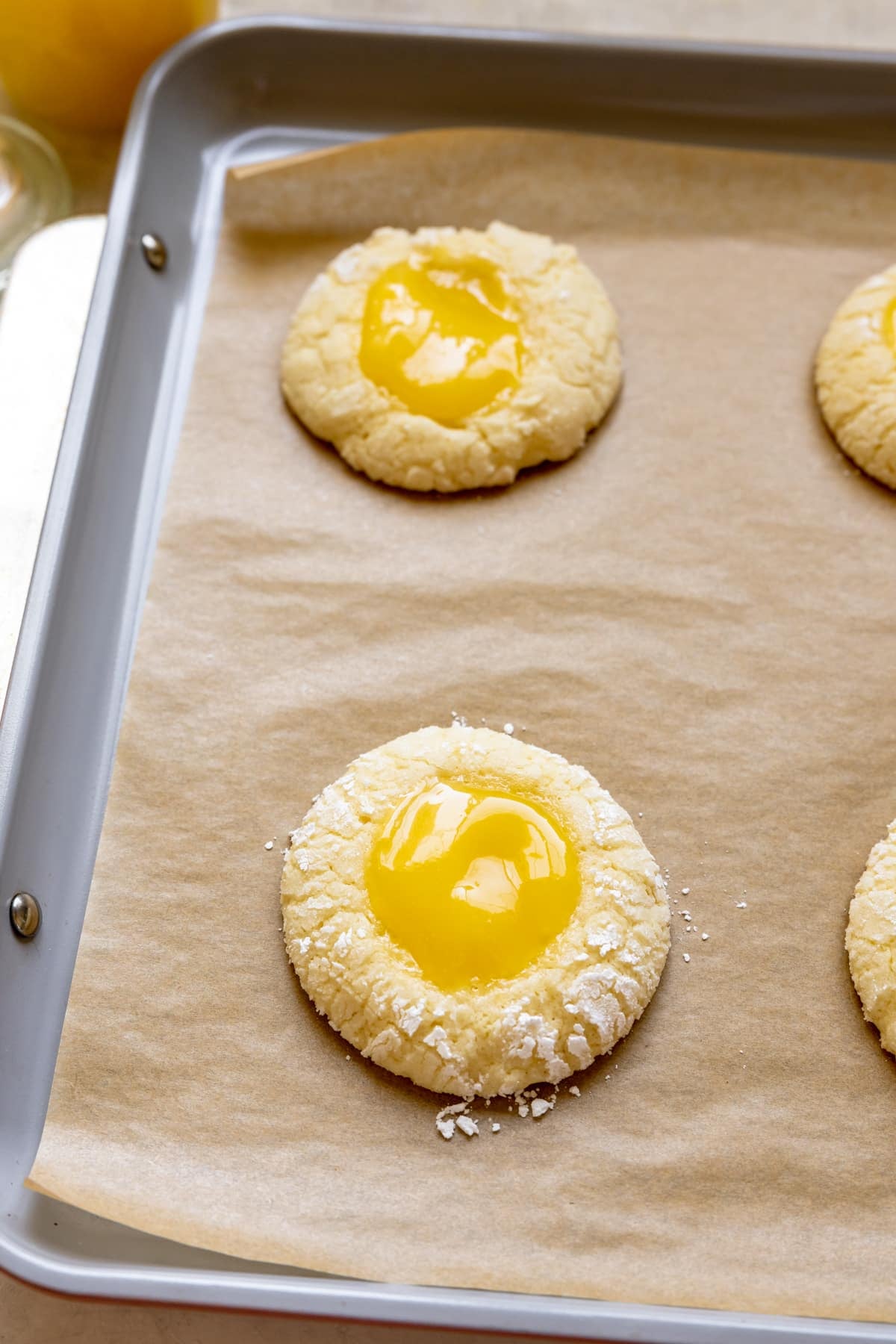 freshly baked lemon cookies with lemon curd on a baking sheet lined with parchment paper. 