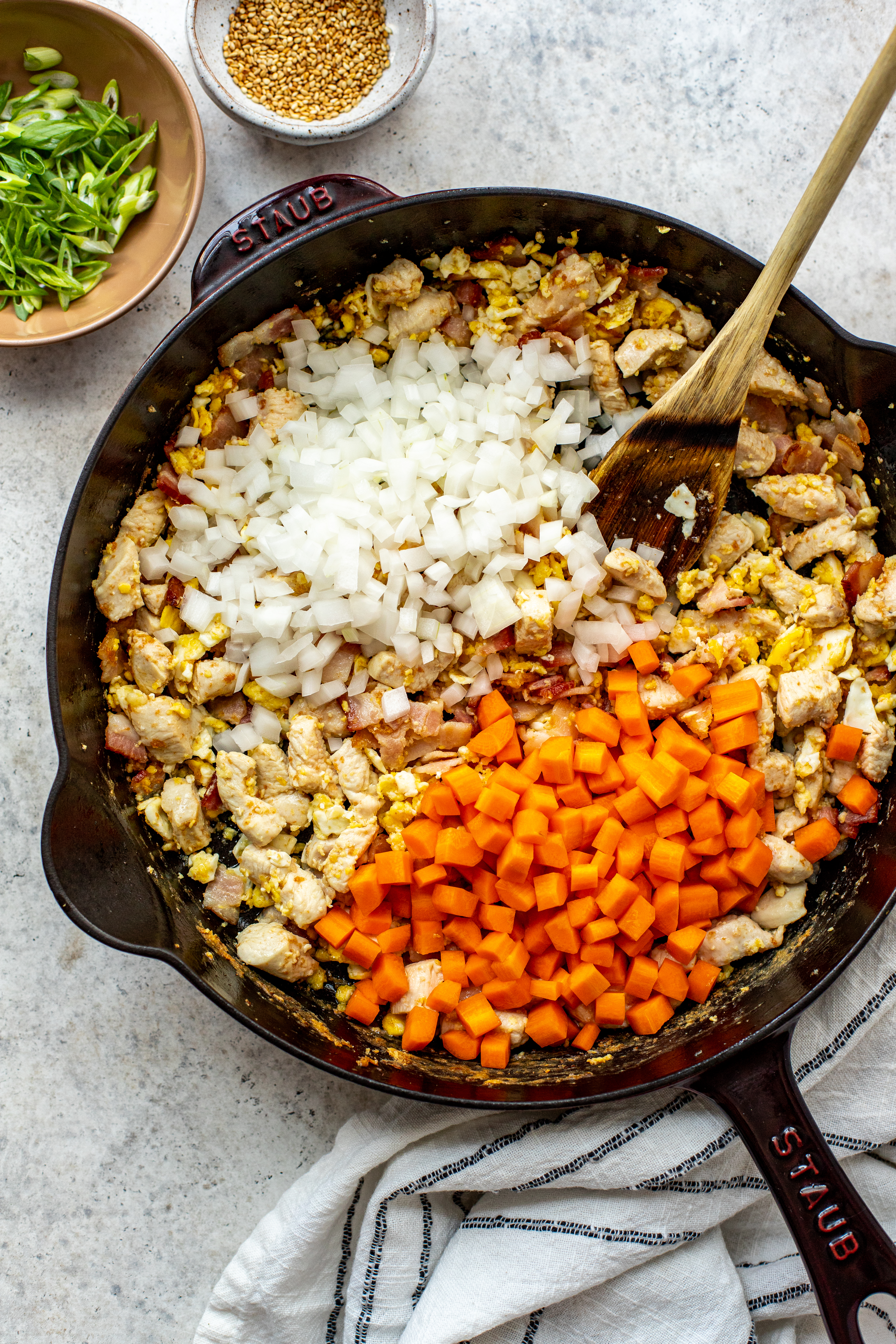 carrots and onions in a cast iron pan with chicken, bacon and scrambled eggs. 
