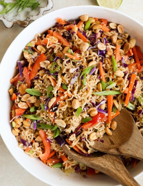 white bowl filled with an asian salad with ramen noodles, chopped veggies, and peanuts