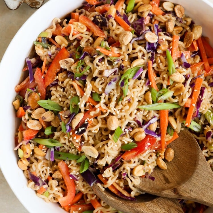 white bowl filled with an asian salad with ramen noodles, chopped veggies, and peanuts